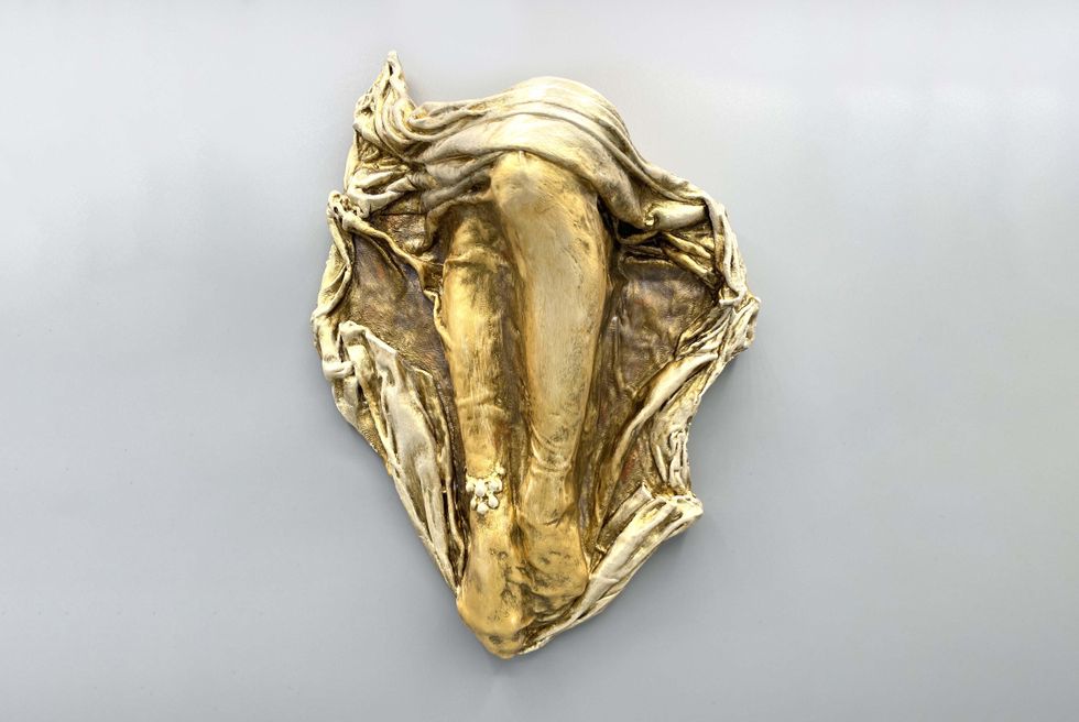 A bronze sclupture of legs on a fabric