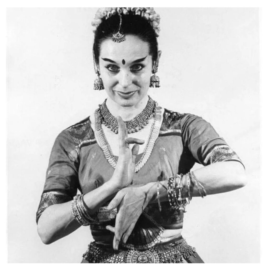 A black-and-white photo of a young Vetra in classical Indian dress, her hands held delicately in front of her chest.